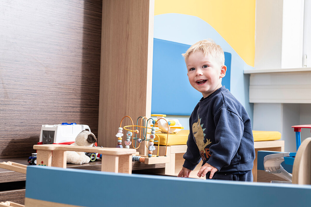 Kleiner Junge lächelt in einem Spielbereich – Szene einer kindgerechten Beratung.